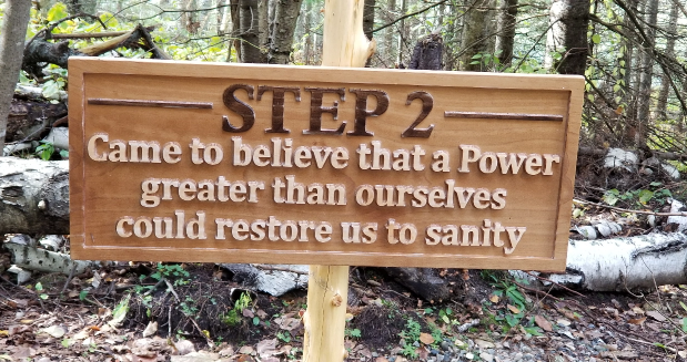 a carved wooden sign that says "Step 2: Came to believe that a Power greater than ourselves could restore us to sanity."