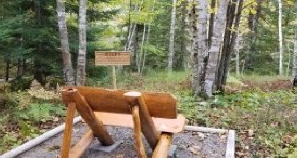 a wooden bench overlooking the woods and the Step 9 sign.