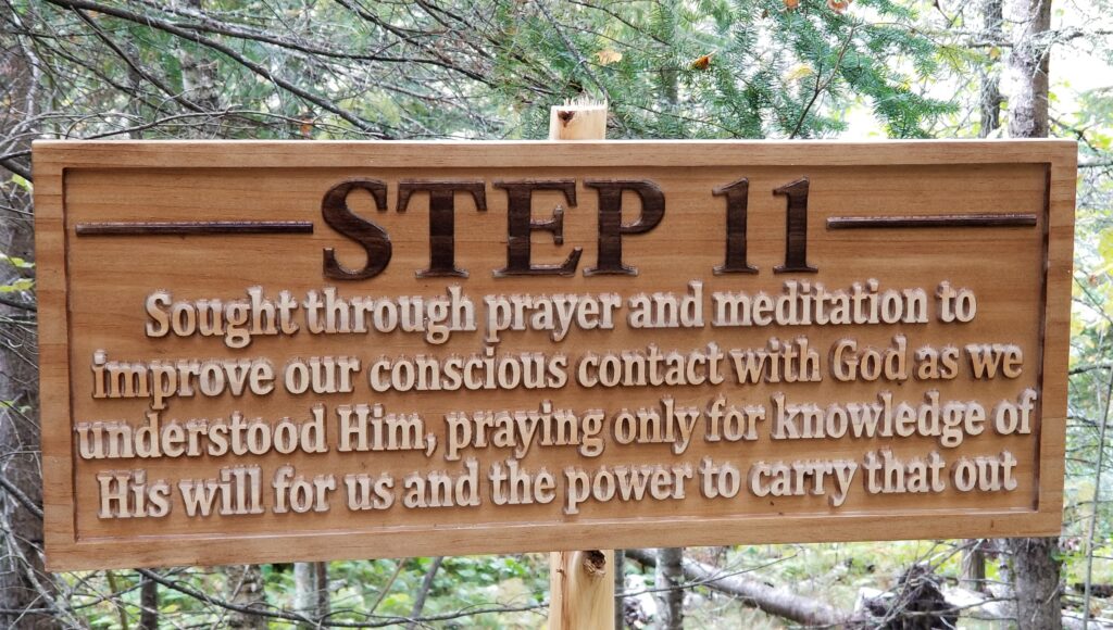 a carved wooden sign that says "Step 11: Sought through prayer and meditation to improve our conscious contact with God as we understood Him, praying only for knowledge of His will for us and the power to carry that out."