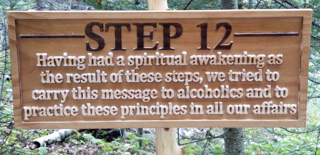 a carved wooden sign that says "Step 12: Having had a spiritual awakening as the result of these steps, we tried to carry this message to alcoholics and to practice these principles in all our affairs."