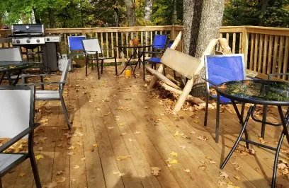 a large deck with tables and a gas grill.